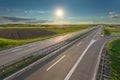 Open freeway through illuminated green agricultural fields Royalty Free Stock Photo