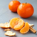 Open fresh mandarin with cinnamon sticks on gray background