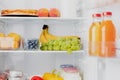 Open fridge or refrigerator door filled with fresh fruits, vegetables, juice Royalty Free Stock Photo