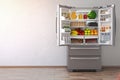 Open fridge refrigerator full of food in the empty kitchen inte
