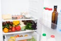 Open fridge with vegetables and dairy products inside Royalty Free Stock Photo