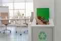 Open full trash bin in modern office. Waste recycling