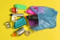 Open garbage bag with plastic bottles and can scattered on yellow background Royalty Free Stock Photo