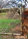 OPEN GATE ATTACHED TO RUSTED METAL POST