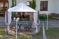 Open gazebo with benches on the lawn with lanterns near the road