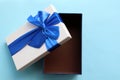 Open gift box with blue ribbon on blue background. Fathers day present for dad. Top view, copy space Royalty Free Stock Photo