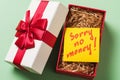 Open gift box with a note inside on a green background. Concept on the topic of lack of money for gifts Royalty Free Stock Photo