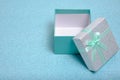 Open gift box with turquoise ribbon and bow on shiny background Royalty Free Stock Photo