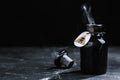 Open glass bottle of smoking poison with warning sign on black table. Space for text