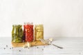 Open glass jars with canned vegetables on a white wooden table. Artichoke in oil, pickled gherkins and small red hot peppers are Royalty Free Stock Photo