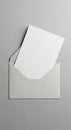 An open gray envelope placed on a smooth, light gray surface contains a blank white Royalty Free Stock Photo