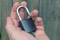 An open gray padlock with a key on the open palm