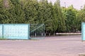 An open green iron gate and a white barrier on the street on gray asphalt near the concrete wall Royalty Free Stock Photo