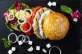 Open hamburger lies on the slate tile. Royalty Free Stock Photo