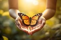 Open hands holding a butterfly over sun rays background. Saving nature and environment concept