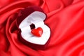 Open heart-shaped gift box with glass heart on red satin fabric background Royalty Free Stock Photo