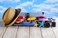 Open holiday suitcase; summer hat, towel, tanning oil, photo camera; flip flops on wooden table Royalty Free Stock Photo