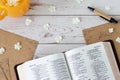 Open holy bible book with a cup of tea, old paper, pen, and white flowers on wooden table, top view Royalty Free Stock Photo