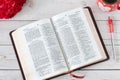 Open Holy Bible Book with fresh red flowers and a cup of a warm coffee cup on a wooden table Royalty Free Stock Photo