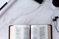 Open holy bible book, notebook, smartphone, earphones, and coffee cup on white marble background, top view, copy space Royalty Free Stock Photo