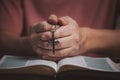 Open holy bible book with people hands folding and holding cross necklace in the middle book pray to God Royalty Free Stock Photo