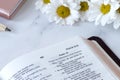 Open holy bible book, Psalm 10 verses with flowers on white marble table