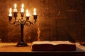 Open Holy Bible and candle on a old oak wooden table. Royalty Free Stock Photo