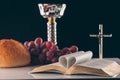 open holy bible, christian cross and chalice on table,