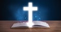 Open holy bible with glowing cross in the middle Royalty Free Stock Photo