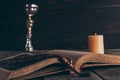 open holy bible with rosary, chalice and candle on wooden table, Royalty Free Stock Photo