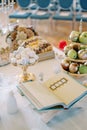 Open holy book on a stand on a table next to fruit in vases, pastries, sugar cones and nuts. Tradition of Sofreh Aghd Royalty Free Stock Photo