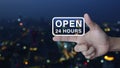 Open 24 hours icon on finger over blur colorful night light modern office city tower and skyscraper, Business full time servi