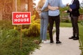 OPEN HOUSE sign and realtor showing potential buyers property for sale, outside. Cropped view