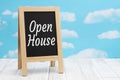 Open House sign on standing chalkboard on weathered wood