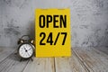 Open 24 Hrs. 7 day Service text message and alarm clock on wooden background Royalty Free Stock Photo
