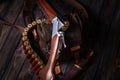 An open hunting rifle with cartridges and a knife in a leather case, lying on the wooden background Royalty Free Stock Photo