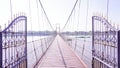 Open the iron door, walkway, suspension bridge over the river, wooden floor under the white cloudy sky, natural sunlight Royalty Free Stock Photo