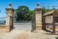 Open iron gate with two stone side columns, entrance to GenovÃ©s park, CÃ¡diz SPAIN Royalty Free Stock Photo