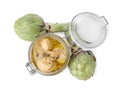 Open jar of delicious artichokes pickled in olive oil and fresh vegetables on white background, top view Royalty Free Stock Photo