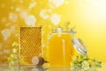 An open jar of honey, honeycombs and wooden spoon on yellow background
