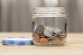 An open jar with small coins of American cents stands on a wooden table, close-up, selective focus. A concept for business and fin Royalty Free Stock Photo