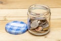 An open jar with small coins of American cents stands on a wooden table, close-up, selective focus. A concept for business and fin Royalty Free Stock Photo