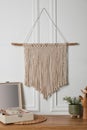 Open jewelry box and decor elements on table near white wall with stylish macrame