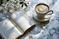 an open journal and a cup of coffee sit on a marble table Royalty Free Stock Photo