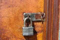 Open key lock hanging on closed orange rusty metal door - not very secure Royalty Free Stock Photo