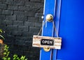 Open label hanging on blue door in garden Royalty Free Stock Photo