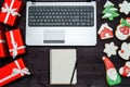 Open laptop computer, Christmas presents, blank notebook and gingerbread cookies on dark wood background, copy space. Royalty Free Stock Photo