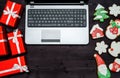 Open laptop computer, Christmas presents and gingerbread cookies on dark wood background, copy space. Top view, flat lay. Royalty Free Stock Photo