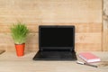 Open laptop, notebook and pen. Home workplace. Green houseplant on the table. Wooden background Royalty Free Stock Photo