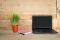 Open laptop, notebook and pen. Home workplace. Green houseplant on the table. Wooden background Royalty Free Stock Photo